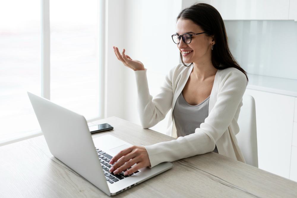 Mujer joven sonriendo mientras trabaja en su computadora portátil en un entorno hogareño luminoso